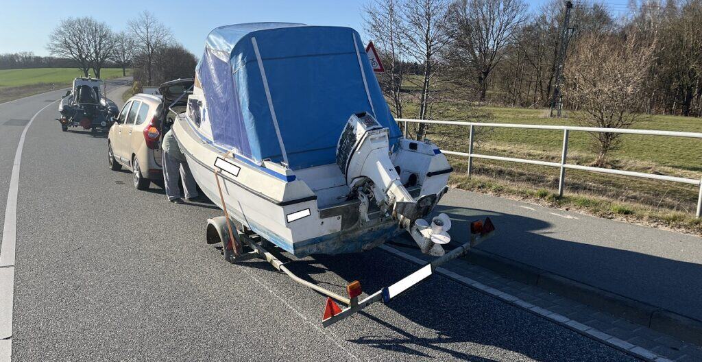 Auto zieht Boot auf Anhänger entlang Landstraße.