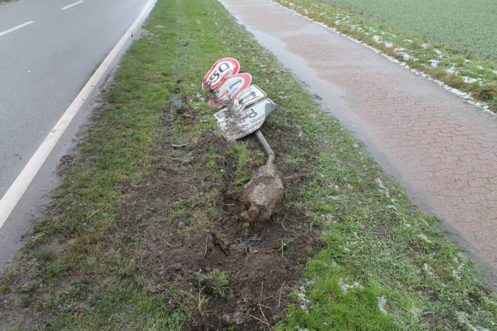 Umgefallenes Verkehrsschild im Matsch an der Straße.